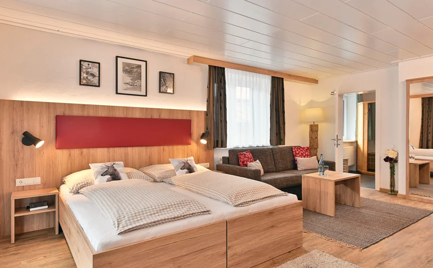 Cozy bedroom with double bed, sofa, and wooden furniture