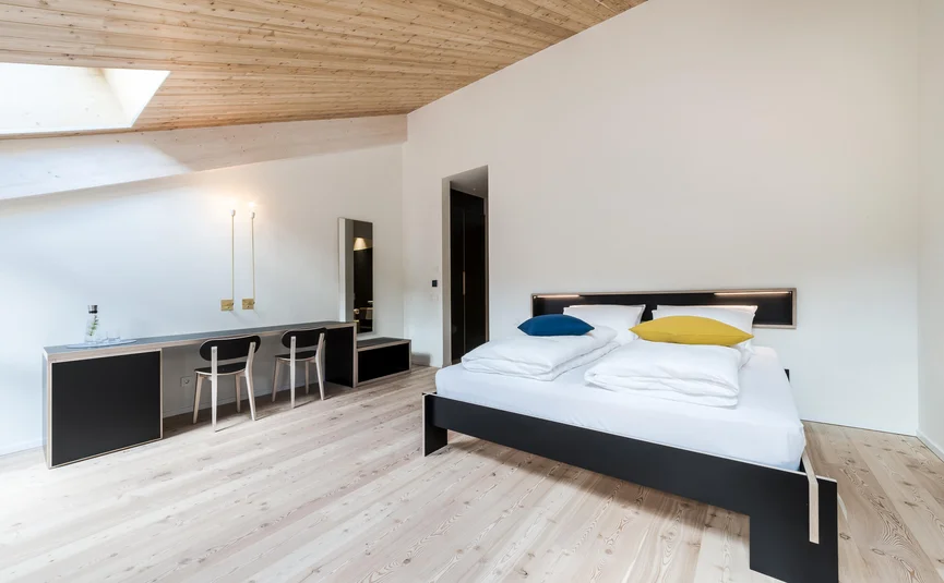 Moderne slaapkamer met houten plafond, tweepersoonsbed en werkplek met twee stoelen