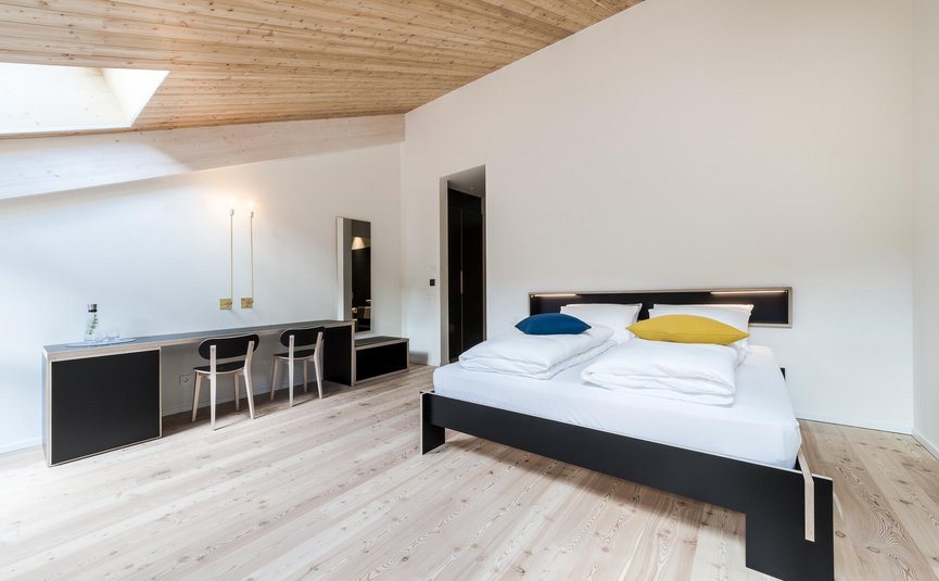 Moderne slaapkamer met houten plafond, tweepersoonsbed en werkplek met twee stoelen