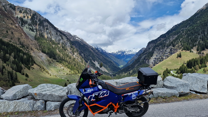 Motorrad vor Alpenlandschaft mit Bergen und Wolken
