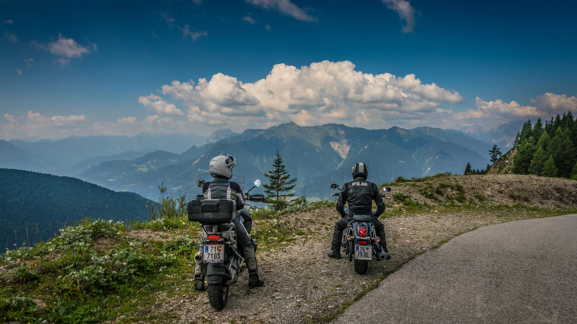 Wissenswertes © Moppetfoto.de Zwei Motorradfahrer auf einem Bergweg mit Blick auf die Alpen