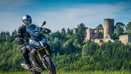Mühlviertel © Moppetfoto.de Motorradfahrer auf Landstraße vor bewaldetem Hügel mit Burgruine