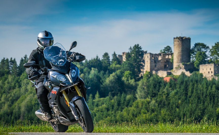 Motorvakantie in het Mühlviertel © Moppetfoto.de Motorrijder op landweg met beboste heuvel en kasteelruïne