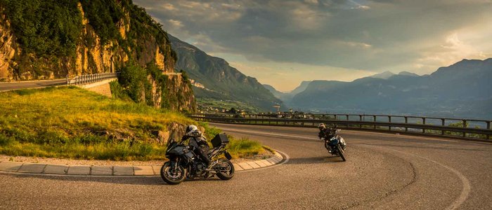 Zwei Motorradfahrer fahren eine kurvige Bergstraße bei Sonnenuntergang