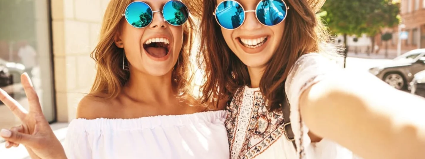 Girlfriend days Two smiling young women wearing sunglasses taking a selfie outside