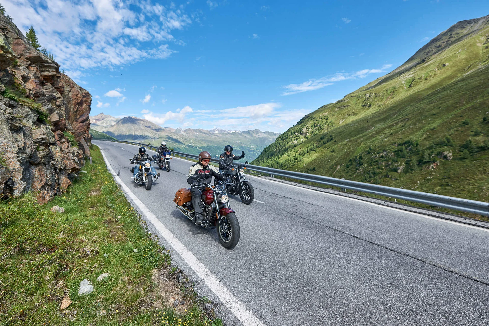 Motorradfahrer fahren auf einer Bergstraße bei sonnigem Wetter