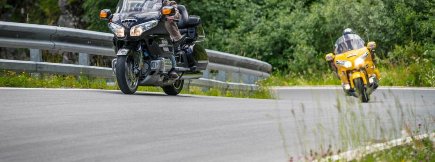 Tourenjagd der 1.000 Möglichkeiten für Biker Zwei Motorradfahrer auf kurviger Bergstraße mit grüner Vegetation