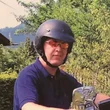 Man wearing helmet sitting on blue Harley-Davidson motorcycle in garden