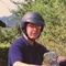 Man wearing helmet sitting on blue Harley-Davidson motorcycle in garden