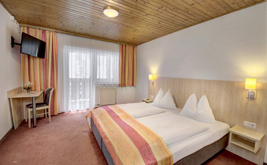Helles Hotelzimmer mit Doppelbett, Schreibtisch und Balkon
