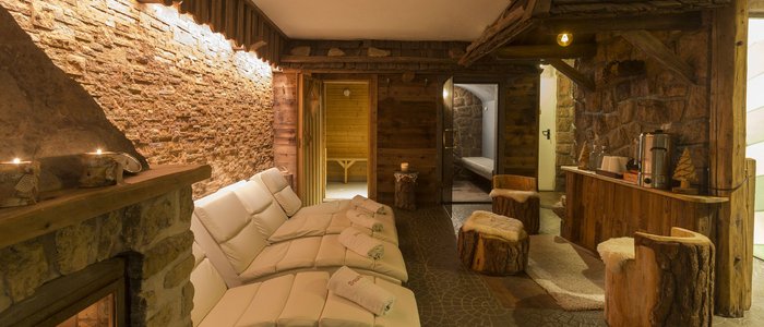 Gemütlicher Wellnessraum mit Kamin, weißen Liegen und rustikalen Holzmöbeln