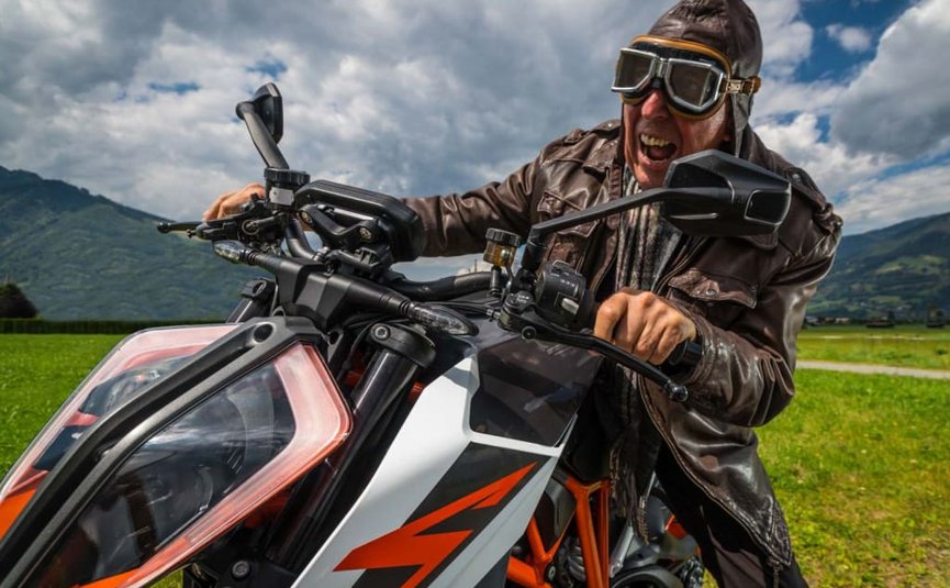 King of the curves offer - as of € 218,- per person Man in leather jacket and goggles on motorcycle outdoors with mountains