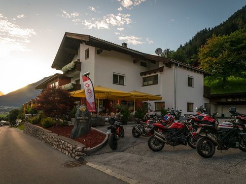 Hotel mit Motorrädern auf Parkplatz bei Sonnenuntergang in den Bergen