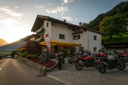 Hotel mit Motorrädern auf Parkplatz bei Sonnenuntergang in den Bergen