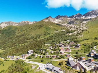 Maurienne Mountain village with houses and green hills under blue sky