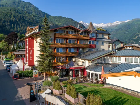 Hotel in den Alpen mit Bergen im Hintergrund und blauen Himmel