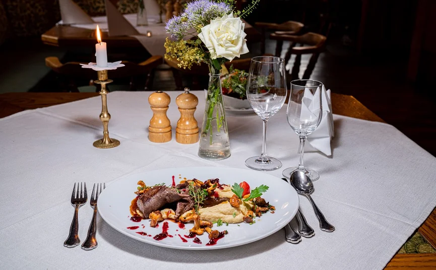 Fine dining plate with game and mushrooms on a set restaurant table