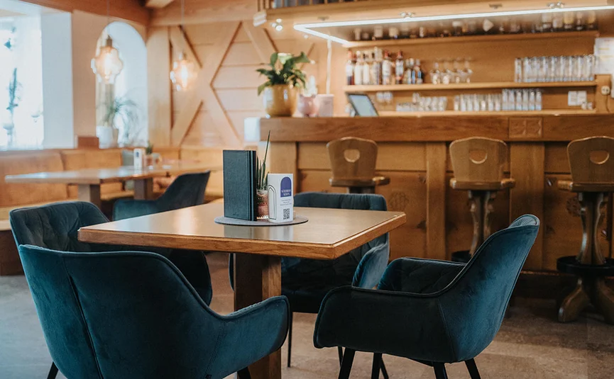 Gemütliche Bar mit Holzmöbeln und blauen Sesseln um einen Tisch