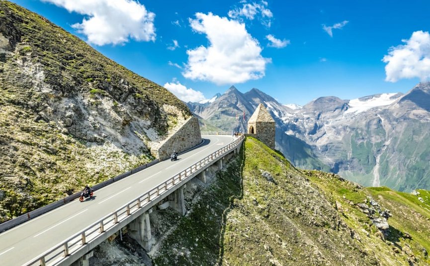 Sternfahrt Motorrad-Special ab € 628,- pro Person Motorräder fahren auf hoher Bergstraße mit Alpen im Hintergrund