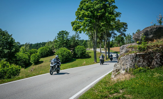 Motorcyclists riding on a winding country road with clear blue sky