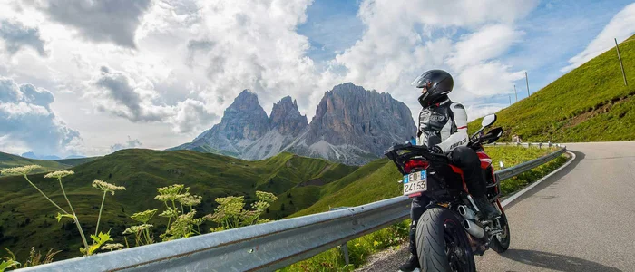 Sella Ronda - Alta Badia © Arik Oberrauch Motorcyclist on mountain road overlooking the Dolomites