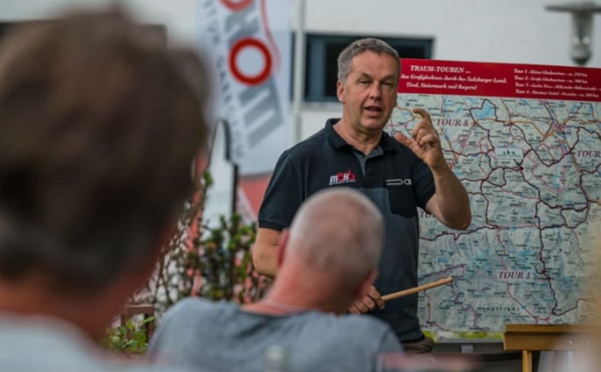 BIKEGENUSS "Großglockner" Mann erklärt eine Karte vor einer kleinen Gruppe im Freien