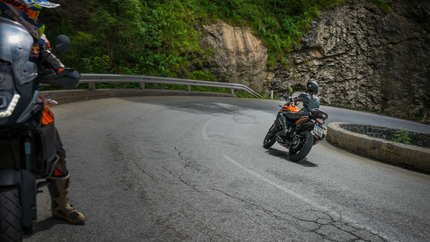 Motorradfahrer fahren eine kurvige Bergstraße mit Felswänden und Grün