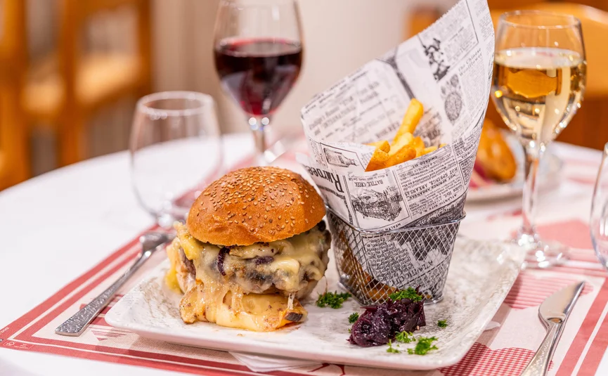 CASA MOHO Saint-François-Longchamp ***S © Jeremi MARIE Photography Cheeseburger met frietjes in krantenpapier en twee glazen wijn op tafel