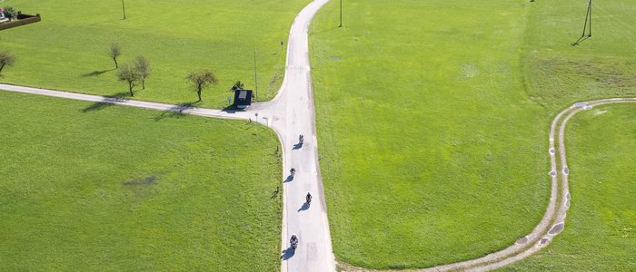 Luchtfoto van een lange landweg met fietsers door groene velden
