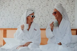 Für Euch Zwei - Zeit, die bleibt Zwei Frauen in Bademänteln und Handtüchern trinken Kaffee im Bett