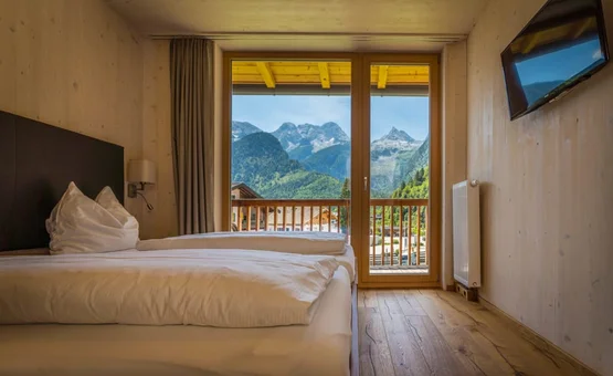 4 Touren Bike Woche Slaapkamer met tweepersoonsbed en uitzicht op bergen door grote ramen