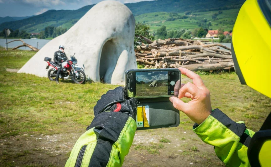 Wachautour Motorradfahrer fotografiert Betonkunstwerk und Motorrad im Freien