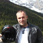 Motorradurlaub in Südtirol und den Dolomiten © compusol.it Mann mit Motorradhelm vor Berg- und Waldlandschaft