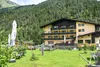 Sammelanfragen © Schönauer Hof - Porsche Gelbes Alpenhotel mit Garten vor bewaldetem Berg im Sommer