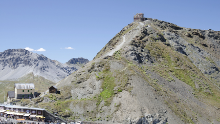 Berg mit Weg und Gebäude auf dem Gipfel, Autos und Menschen unten