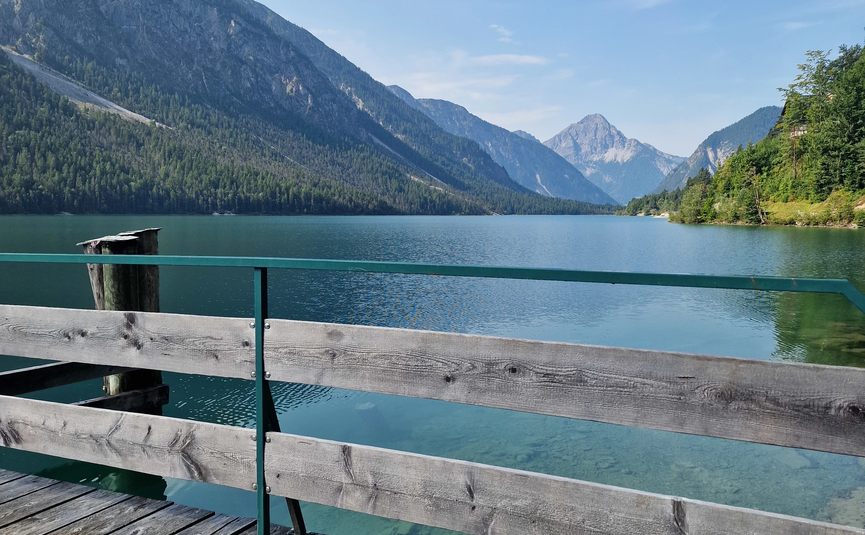 MoHo Schönauer Hof Tour 10 "Lake Tour-Kühtai" Wooden pier on clear mountain lake with view of mountains under blue sky