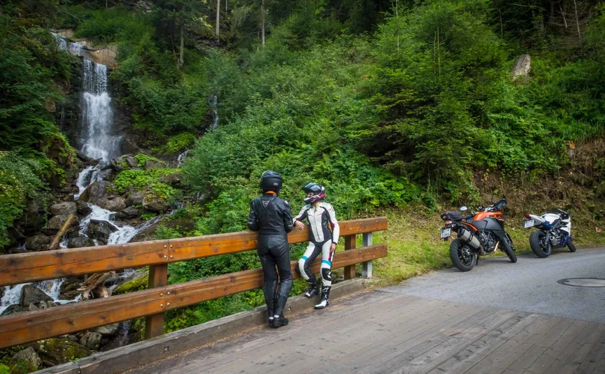 10 Hotel Sonnleiten: Circuit Sudelfeld-Hintersteinersee-Walchsee Twee motorrijders staan op een brug bij een waterval in het bos