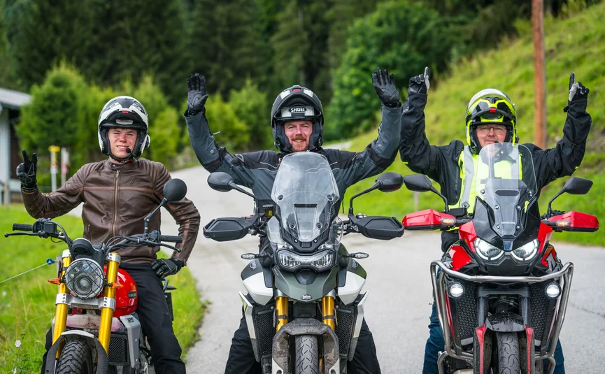 Three motorcyclists in gear and helmets on a country road