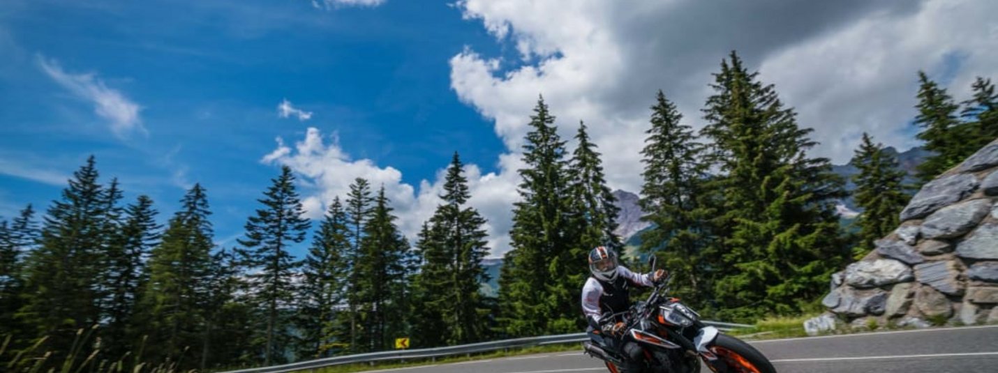 2 days motor bike fun Motorcyclist riding around a curve on mountain road under sunny sky