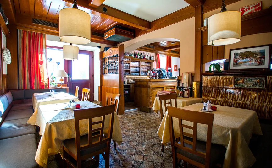 Cozy restaurant with wooden furniture, tables with tablecloths, and warm lighting