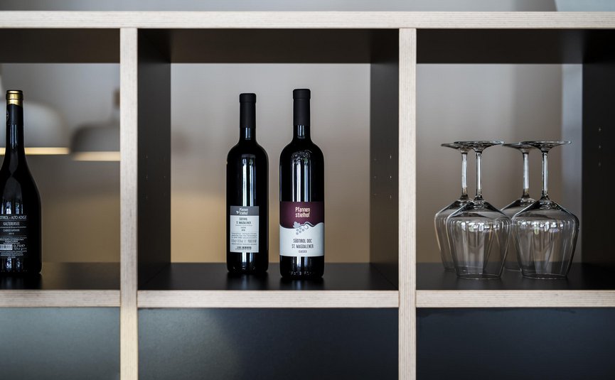 Planken met drie wijnflessen en vier omgekeerde wijnglazen