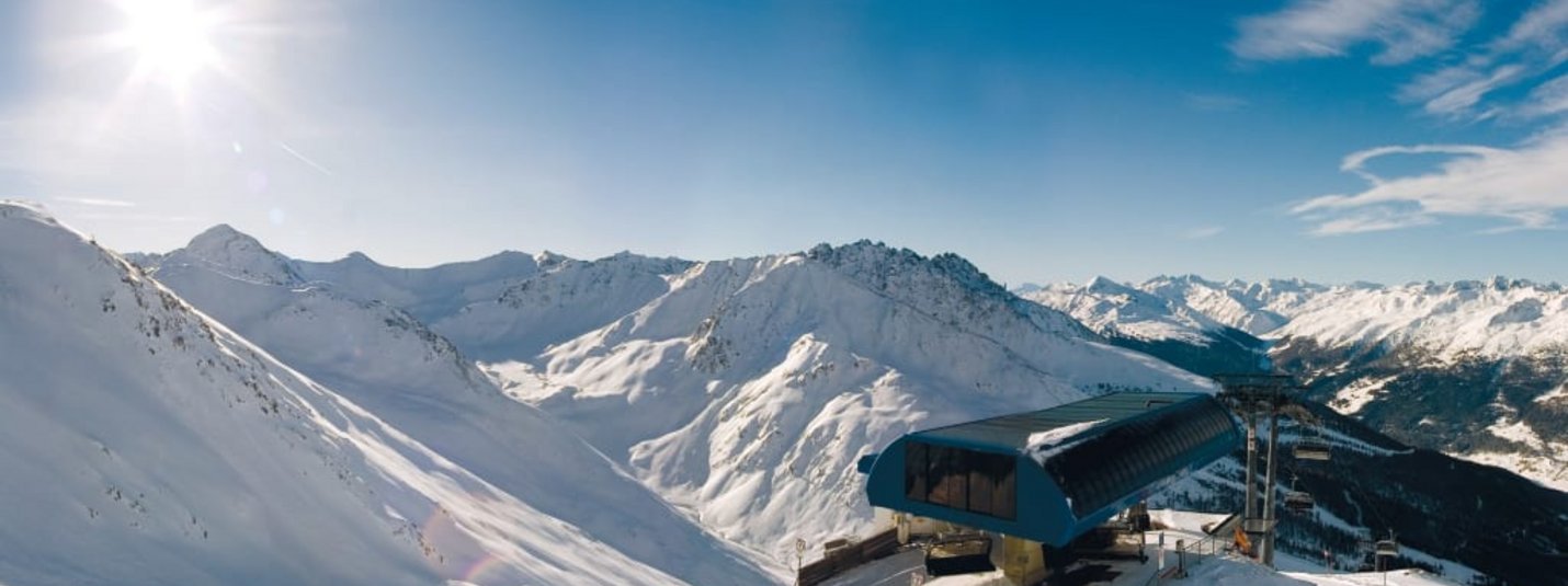 Skiliftstation in schneebedeckten Alpen bei sonnigem Himmel