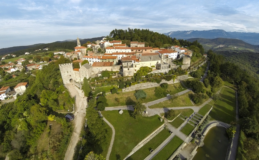 Luchtfoto van een historische vestingstad op een heuvel met omliggende bergen