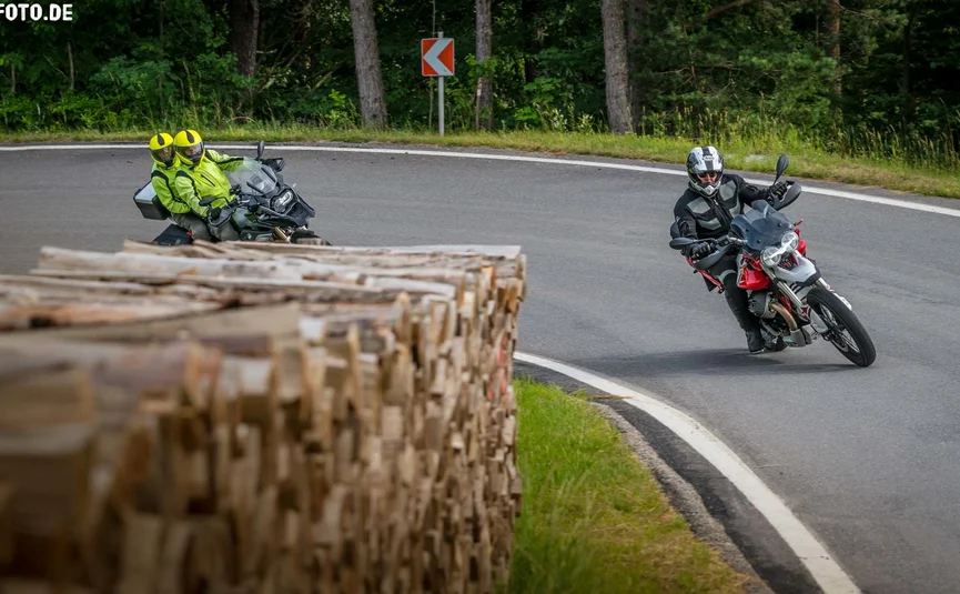 Pre-Alps ...the curvy one Motorcyclists riding on winding country road near stacked firewood