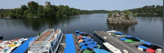 Boat dock on lake with colorful covered boats and forested shores