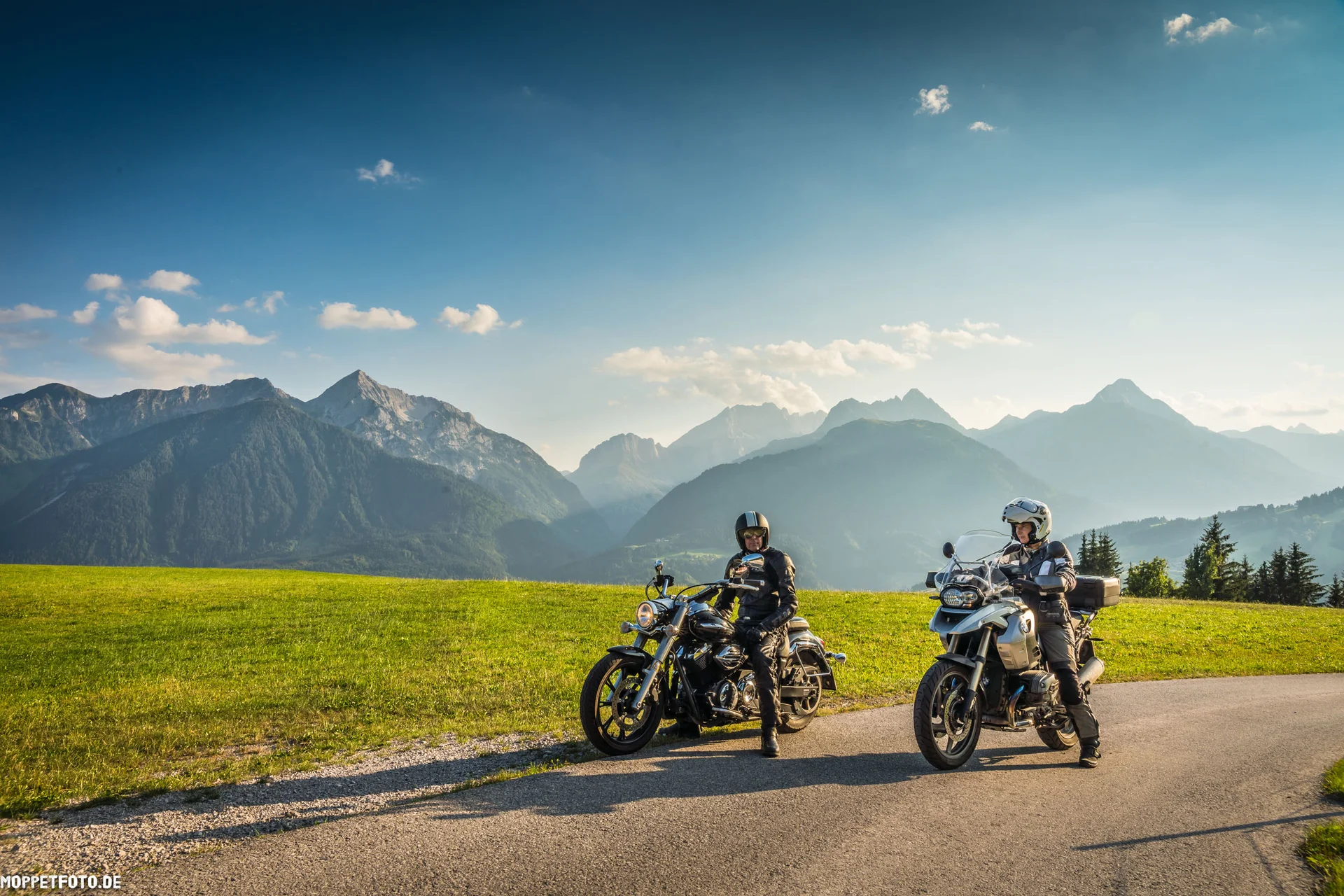 Motorradurlaub © Moppetfoto.de Zwei Motorradfahrer auf Landstraße mit grünen Wiesen und Alpen im Hintergrund
