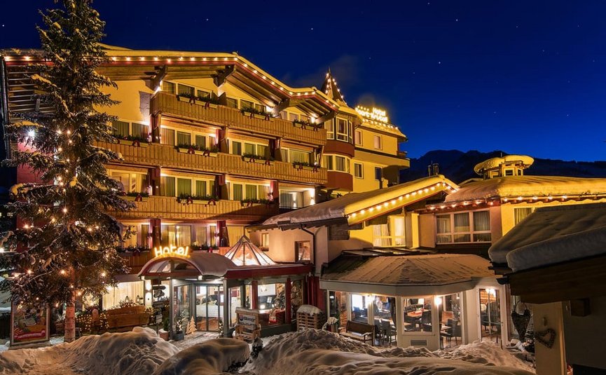 Lit hotel at night in snowy winter with decorated tree