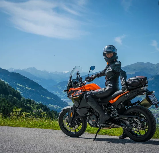 6 Hotel Sonnleiten: After-work tour Kerschbaumsattel Motorrijder in zwarte kleding op oranje motor met bergen op de achtergrond