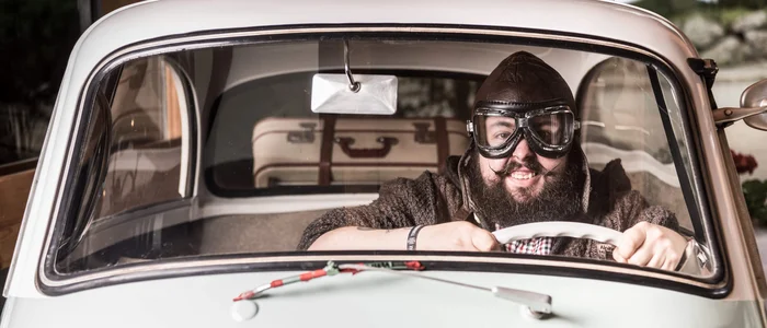 Man with pilot cap and goggles driving a BMW Isetta 300