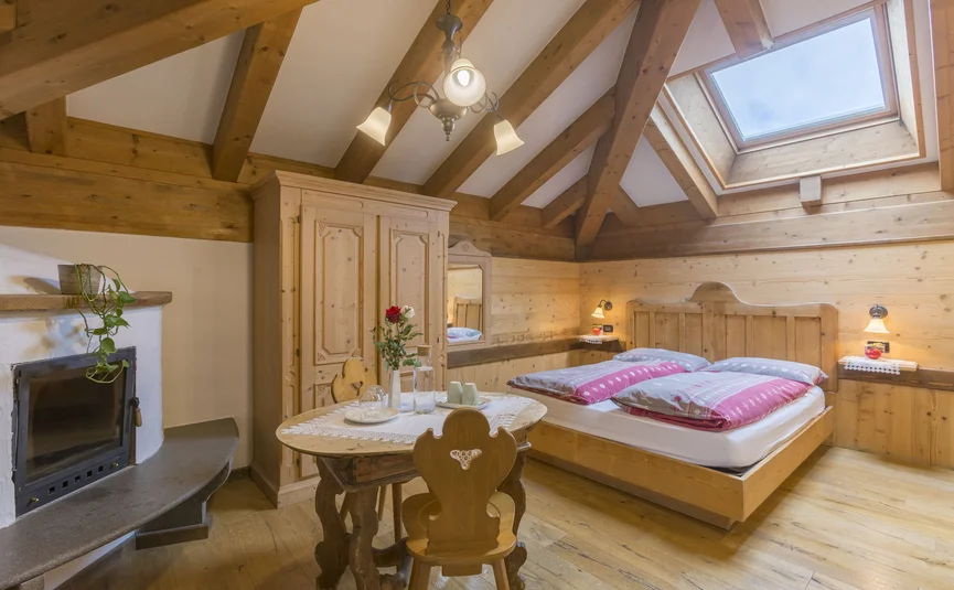 Hotel La Stüa **** © Hotel La Stüa Gemütliches Schlafzimmer mit Holzdecke, Kamin und Dachfenster